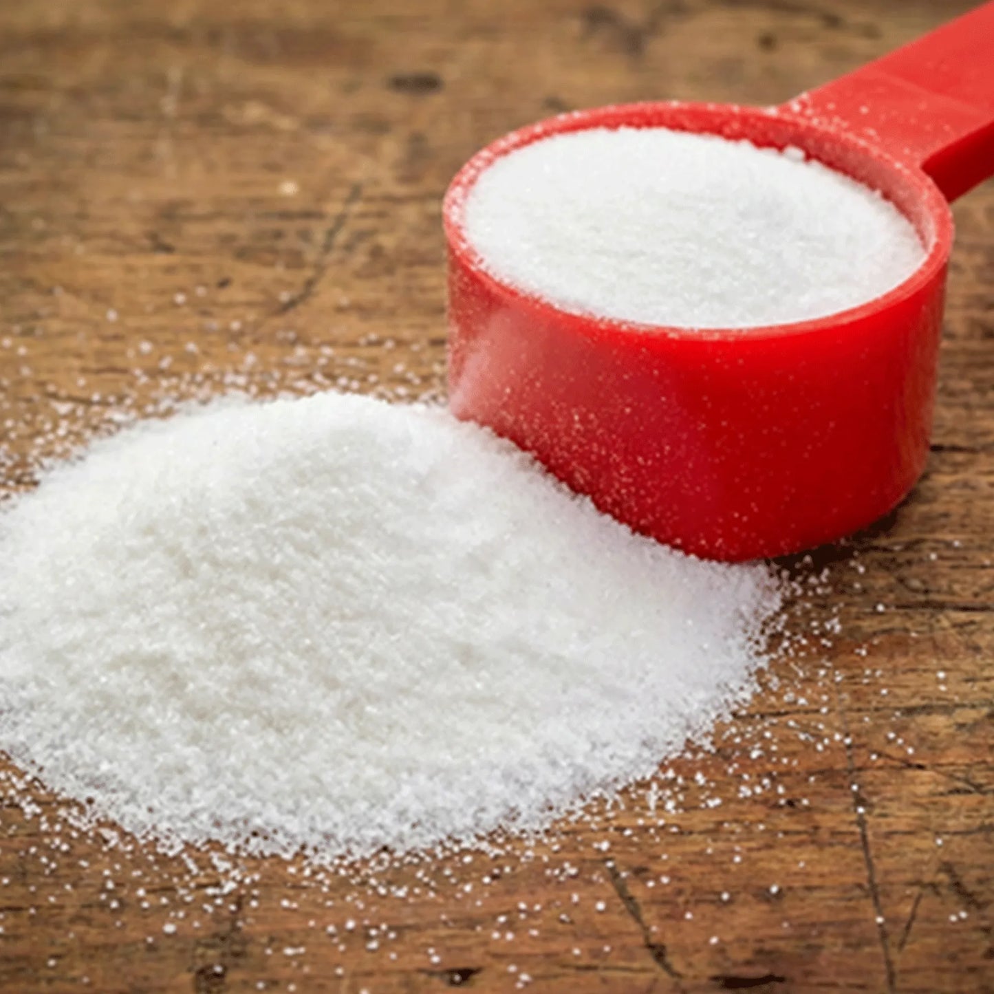 Health E™,"Red measuring scoop with white granules beside spilled pile"