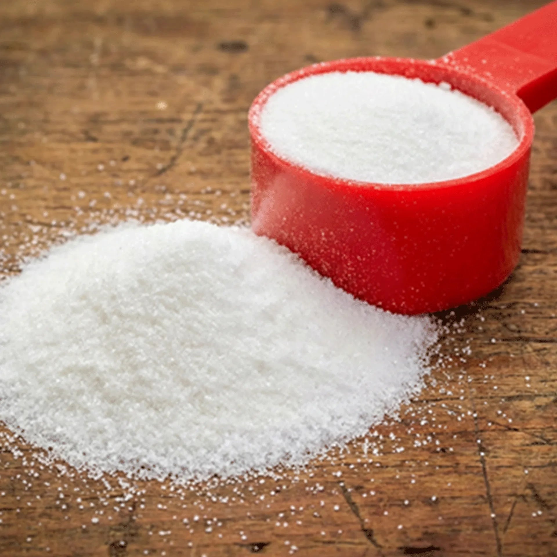 Health E™,"Red measuring scoop with white granules beside spilled pile"