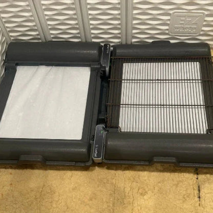 BrilliantPad Grate,"Two black trays opened with white absorbent pads and wire grate insert"