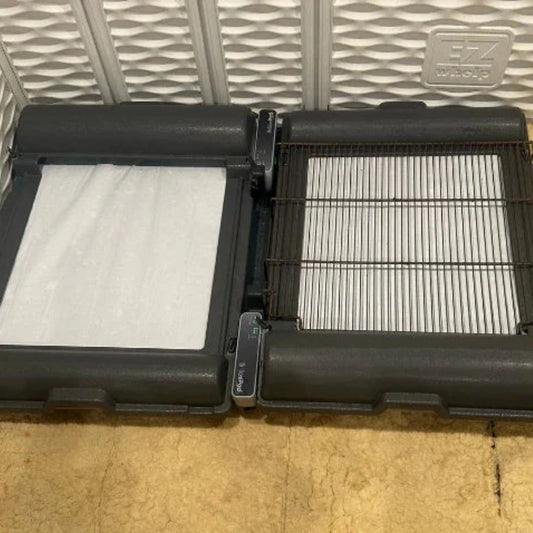 BrilliantPad Grate,"Two black trays opened with white absorbent pads and wire grate insert"